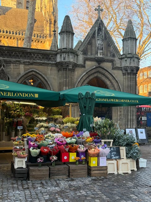 A flower stall set up outdoors in Westminster, featuring an array of fresh floral bouquets and arrangements placed on wooden pallets and small white tables. The flowers include vibrant pink, red, yell